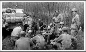 After Liberation, 4/13/45 -
Boo Nunnally, sitting just below the B16 marker on the vehicle.  Patrick Ward, just over Boo's left shoulder being handed a cup. Thomas Morton, middle with a spoon in his left hand. Carl Hansen, in front of Boo wearing glasses.